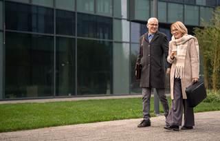 Older man and women in professional clothes walking in front of an office building
