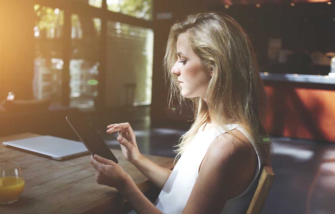 Woman sitting at a table looking at consumer sentiment data on a tablet