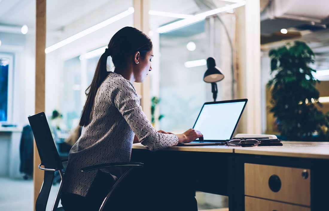 Woman sitting at a desk looking at a computer screen.