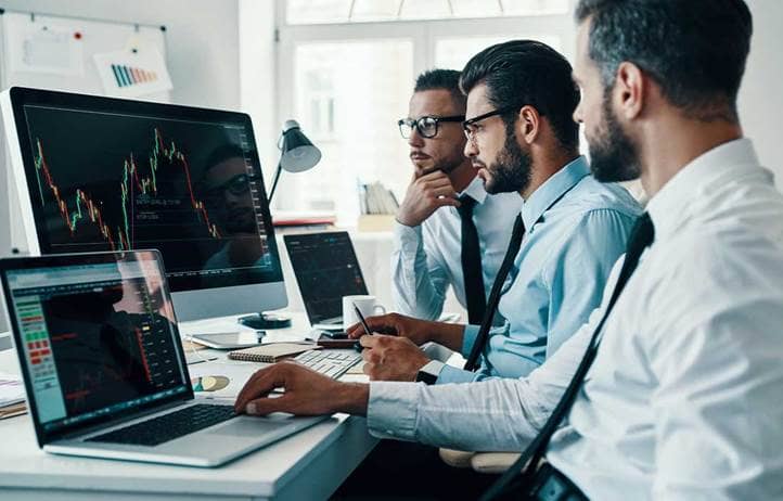 Three men looking at computer screens.