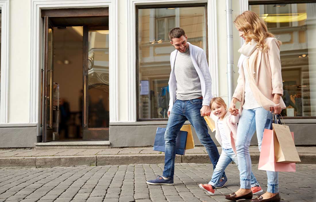 Family walking in the street holding hands and holding retail bags