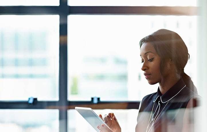 Woman looking down at a tablet in an office.