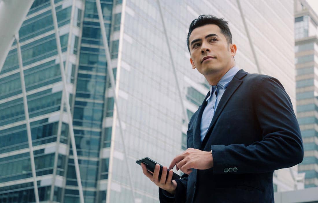 Man in a suit holding his phone and looking to the side.