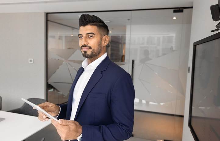 Man in a suit holding a tablet and looking to the side.