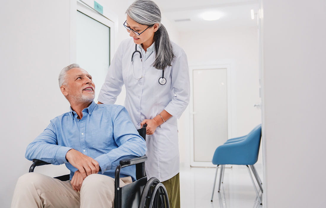 Senior patient being pushed in a wheelchair by a medical staff member